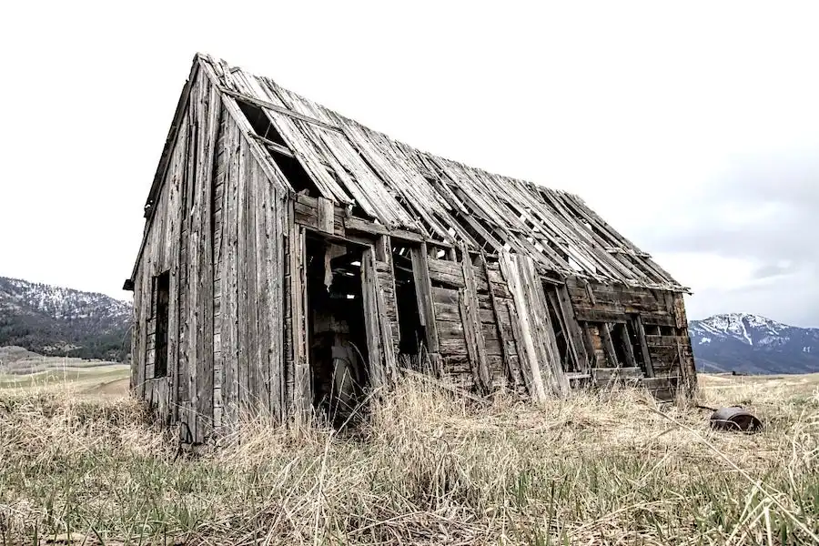 Un vieux bâtiment de bois au milieu d'un champ.