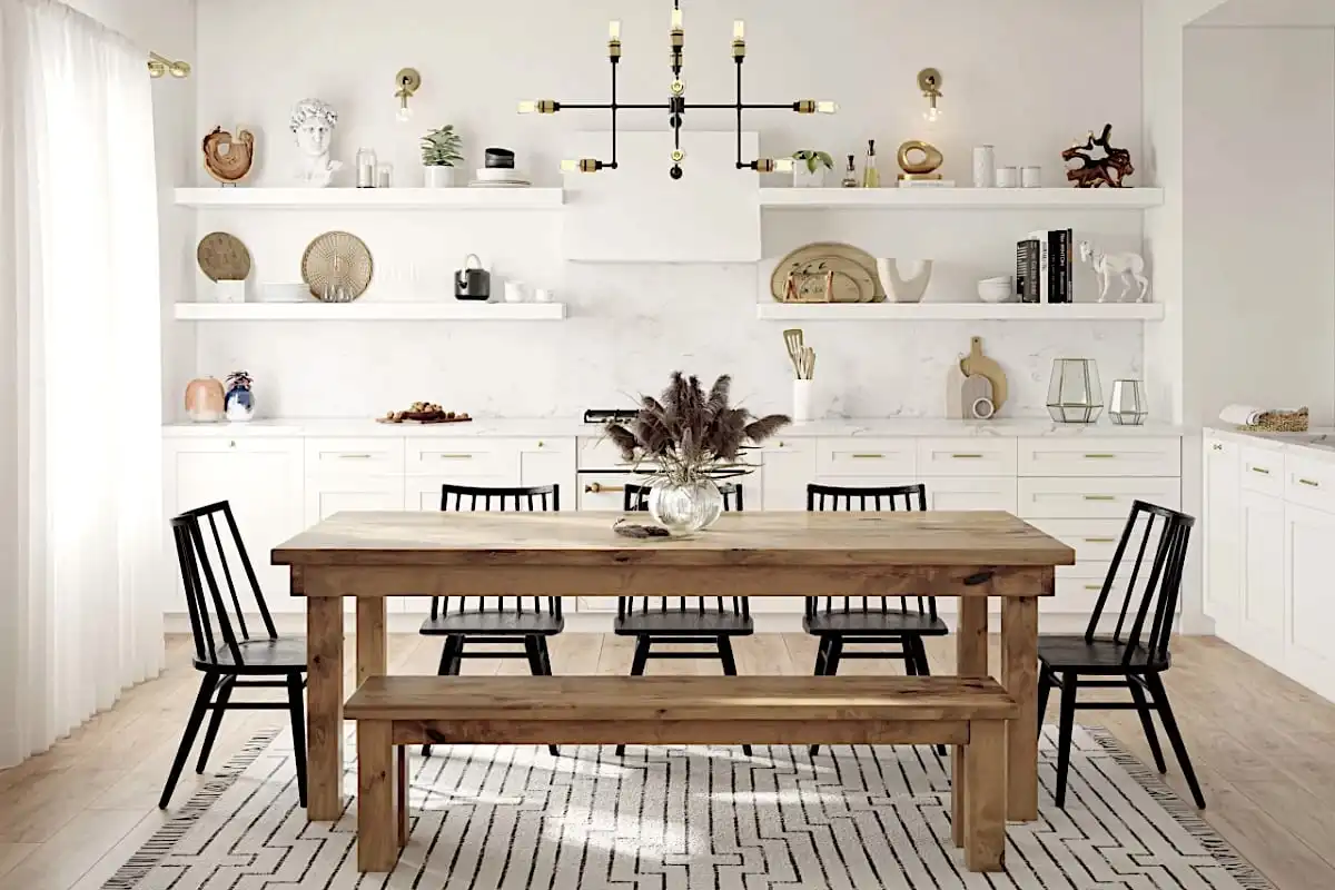 Une salle à manger comprend une table en bois rustique avec des chaises noires et un banc sur un tapis à motifs, des étagères blanches intégrées avec diverses décorations et un lustre moderne.