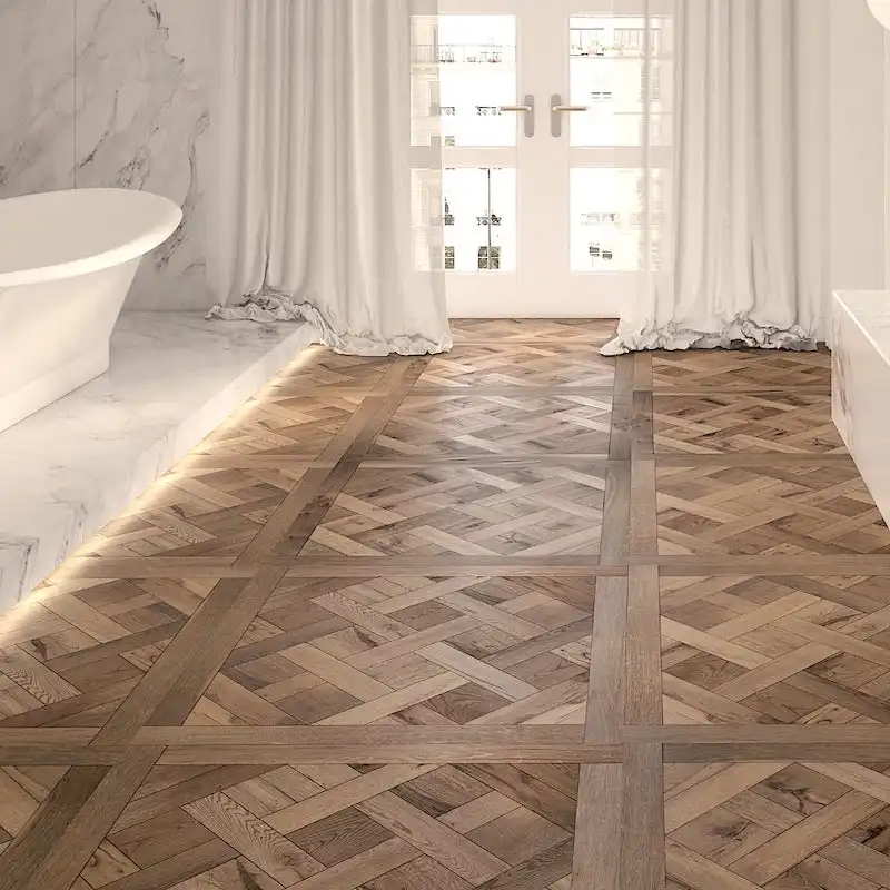  Salle de bains moderne avec baignoire blanche, mur en marbre et grande fenêtre avec rideaux lumineux. Le sol présente un motif complexe de parquet Versailles qui ajoute une touche d'élégance au vieux bois. 