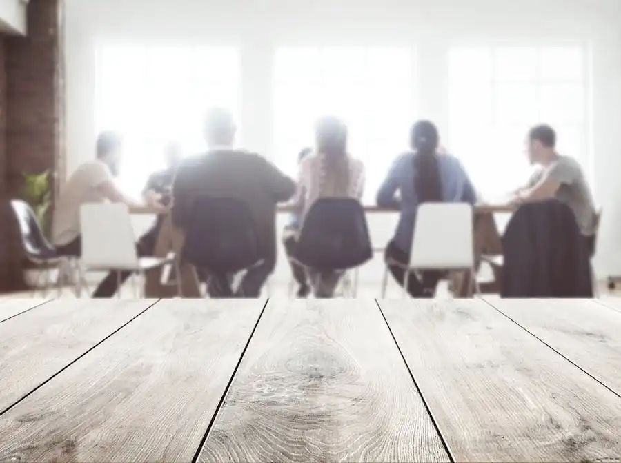 Un groupe de personnes assises autour d’une table en bois rustique dans une salle de conférence.