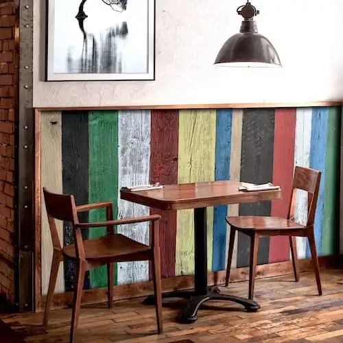  Une table et des chaises en bois dans un restaurant avec un mur en vieux bois coloré. 