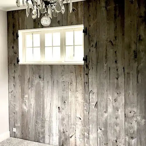  Une pièce avec des boiseries en bardage gris et un lustre 