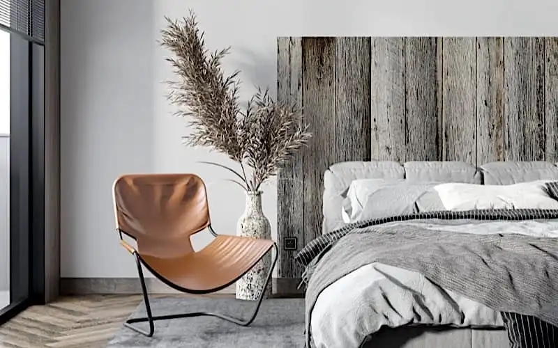 Une chambre avec une tête de lit en vieux bois et une chaise grise