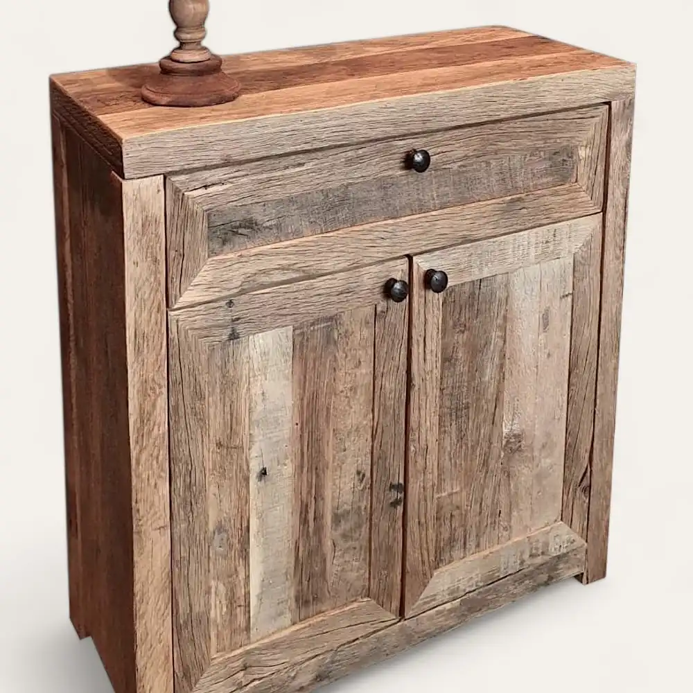 Une armoire en bois avec deux portes et un petit tiroir, au design rustique rappelant le meuble en bois ancien, avec une lampe positionnée sur le dessus.