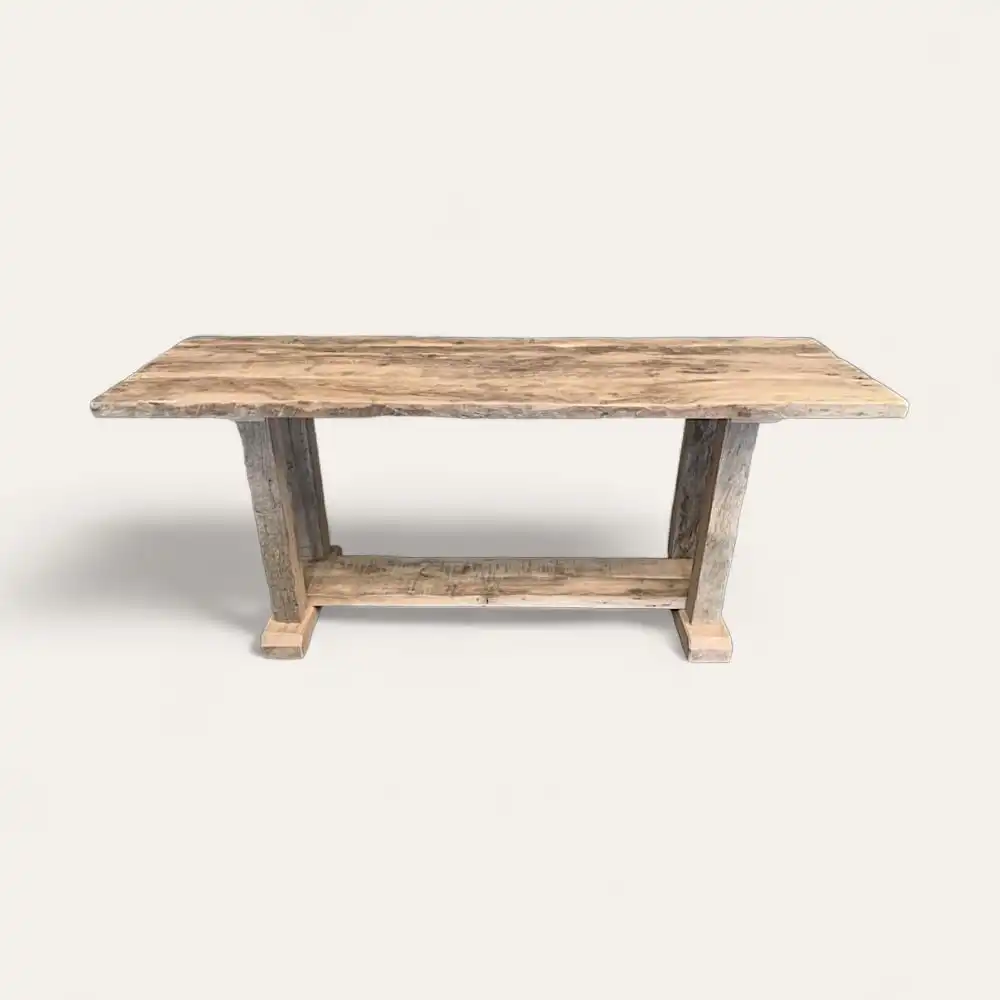  Une table rectangulaire en bois au fini rustique, dotée d'une base à tréteaux des deux côtés. Cette console en bois ancien présente un aspect clair et patiné. 