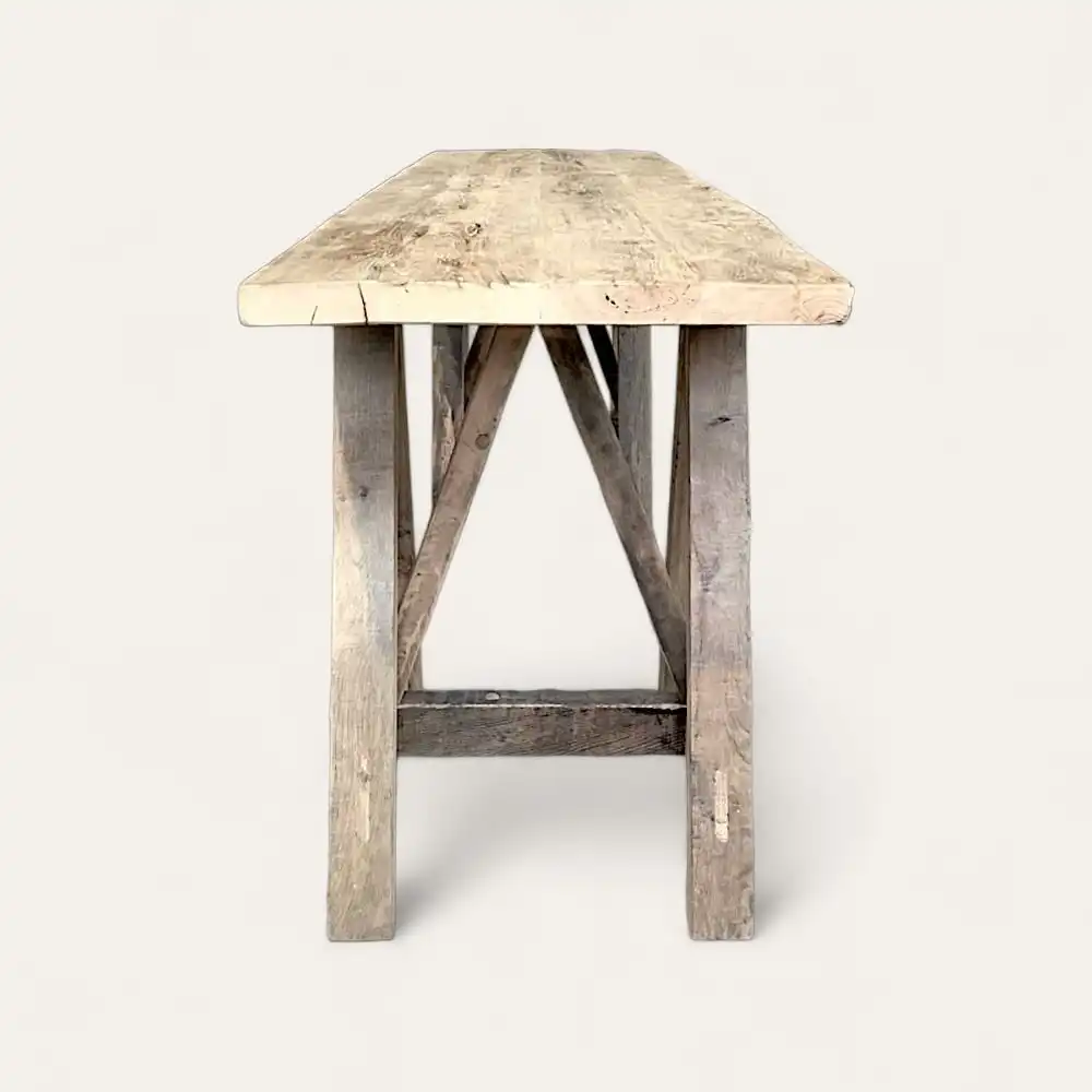  Une table rustique en bois avec un plateau rectangulaire et une base en A, ressemblant à une charmante *console bois ancien*, est présentée sur un fond gris clair. 