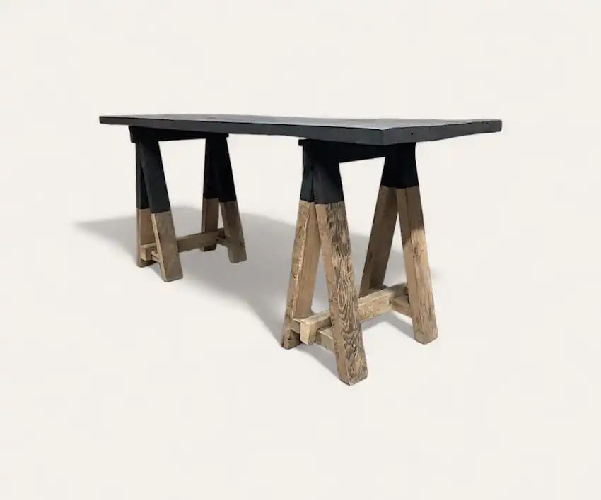 Une table en bois rustique avec un plateau rectangulaire foncé et des pieds de style tréteau, présentant un mélange de bois naturel et d'accents noirs, parfaite pour ajouter une touche de charme de console en bois à n'importe quel espace.