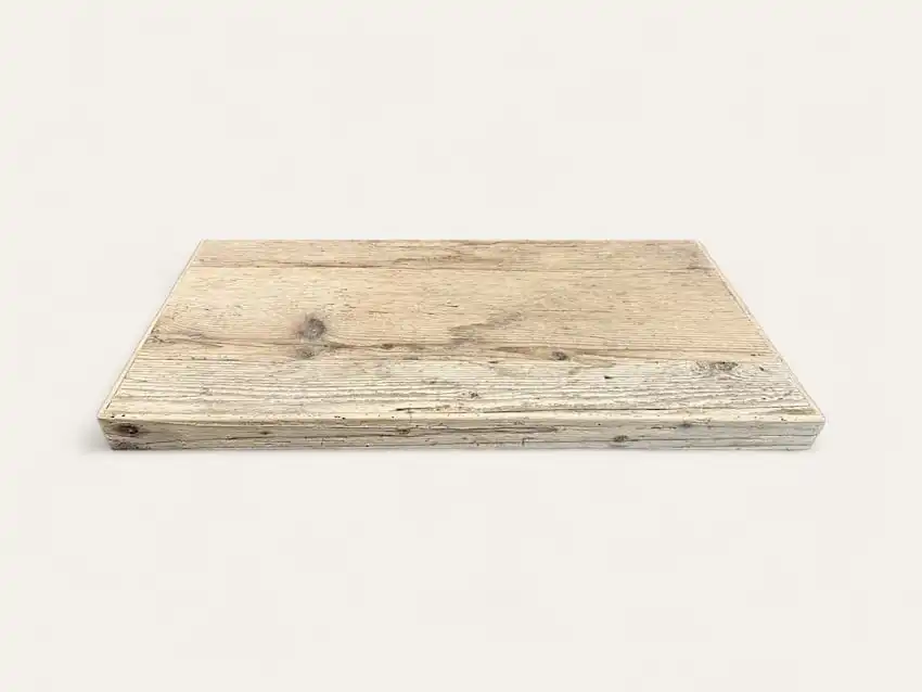 Une planche à découper rectangulaire en bois de couleur claire avec des motifs de grains de bois visibles, rappelant une étagère en bois ancien, sur un fond uni.