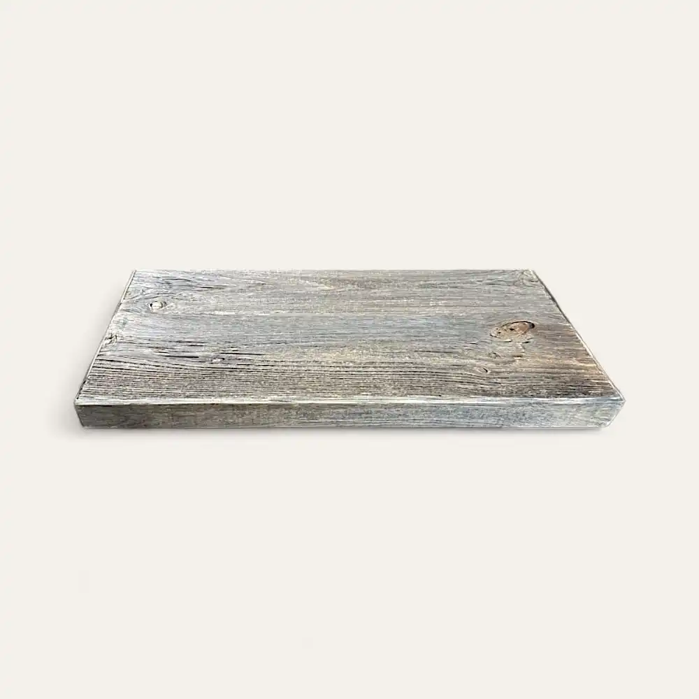 Une planche de bois rectangulaire à l'aspect rustique et patiné, s'apparentant à une étagère bois rustique, repose sur un fond uni blanc cassé. 