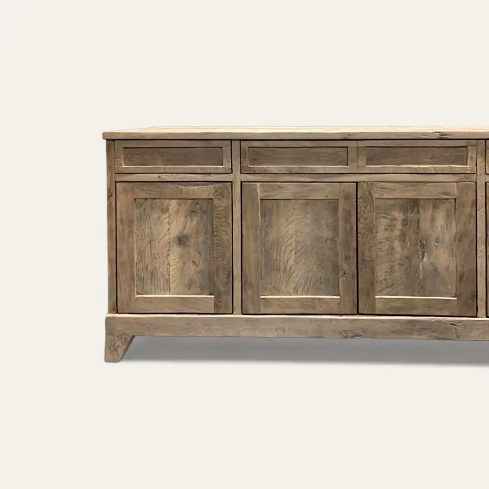  Un buffet en bois au fini rustique, doté de trois tiroirs et de trois portes d'armoire, sur un fond blanc uni, dégage le charme du meuble bois ancien. 