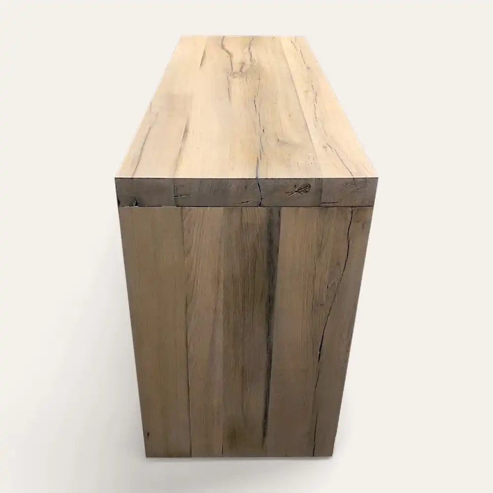  Une caisse rectangulaire en bois à la finition naturelle claire et aux motifs de grains visibles, rappelant un meuble de salle de bain rustique, se dresse sur un fond blanc uni. 