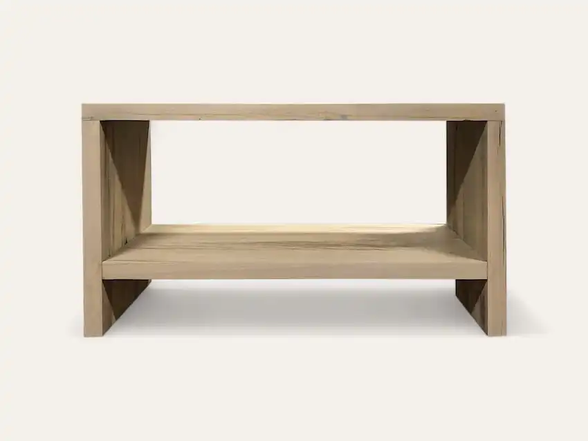Une table basse simple et rectangulaire en bois avec une étagère ouverte sous le plateau, rappelant un meuble en bois ancien, sur un fond uni.