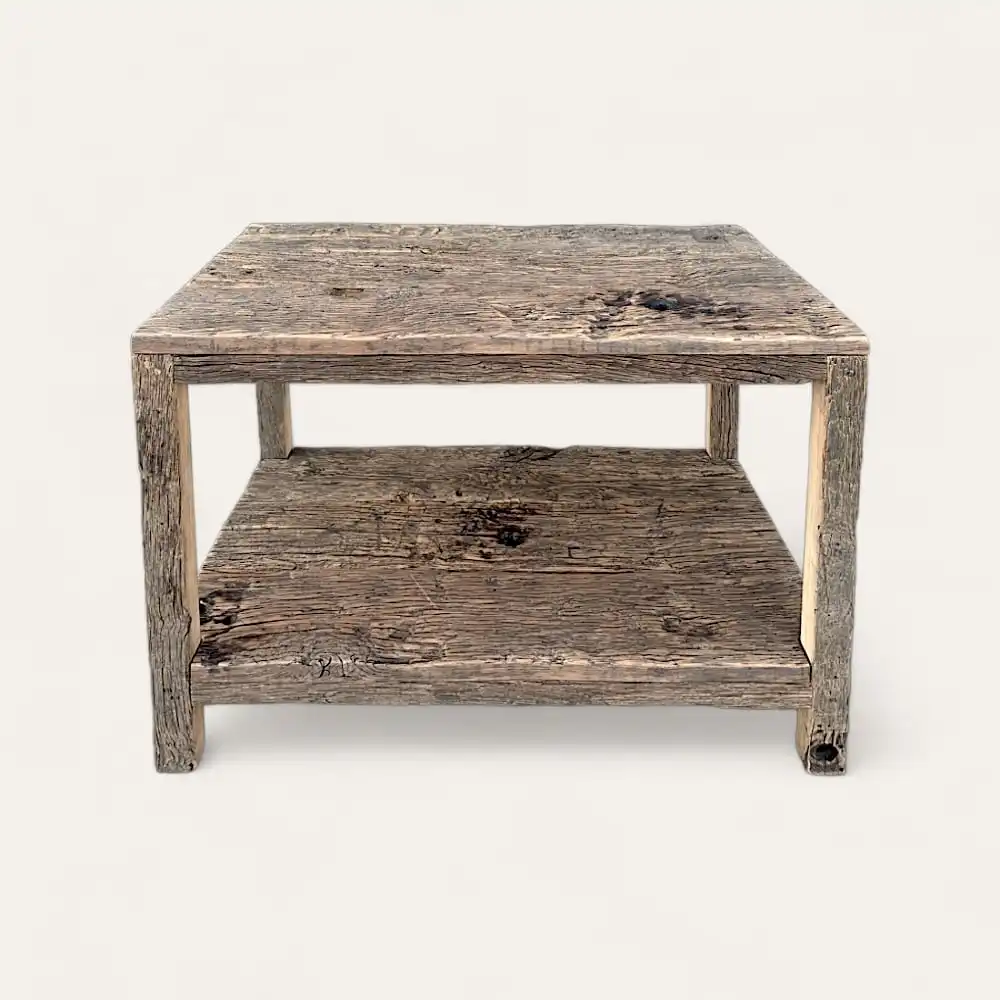  Une table basse carrée en bois à l'aspect patiné, dotée d'une étagère inférieure pour le rangement, incarne le charme d'un meuble bois rustique. 