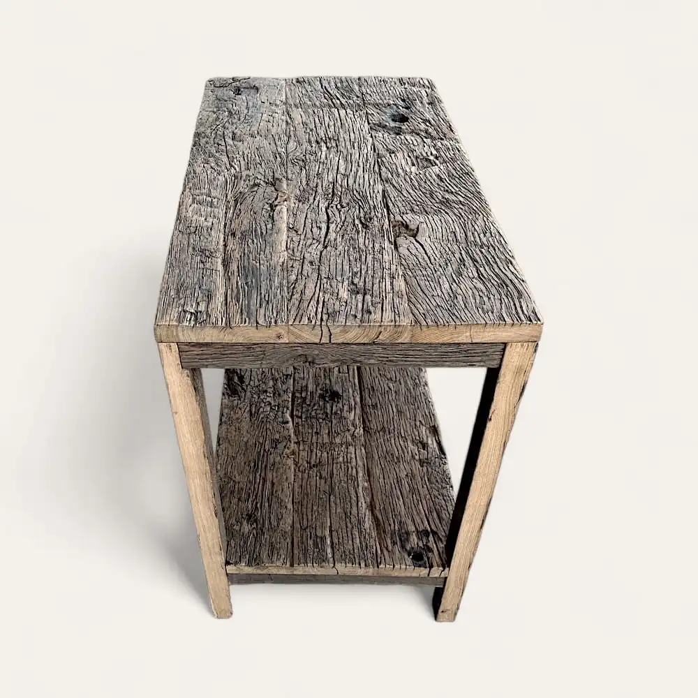 Une table en bois d'aspect rustique et patiné, ressemblant à un meuble ancien bois, comportant une étagère sous le plateau. 