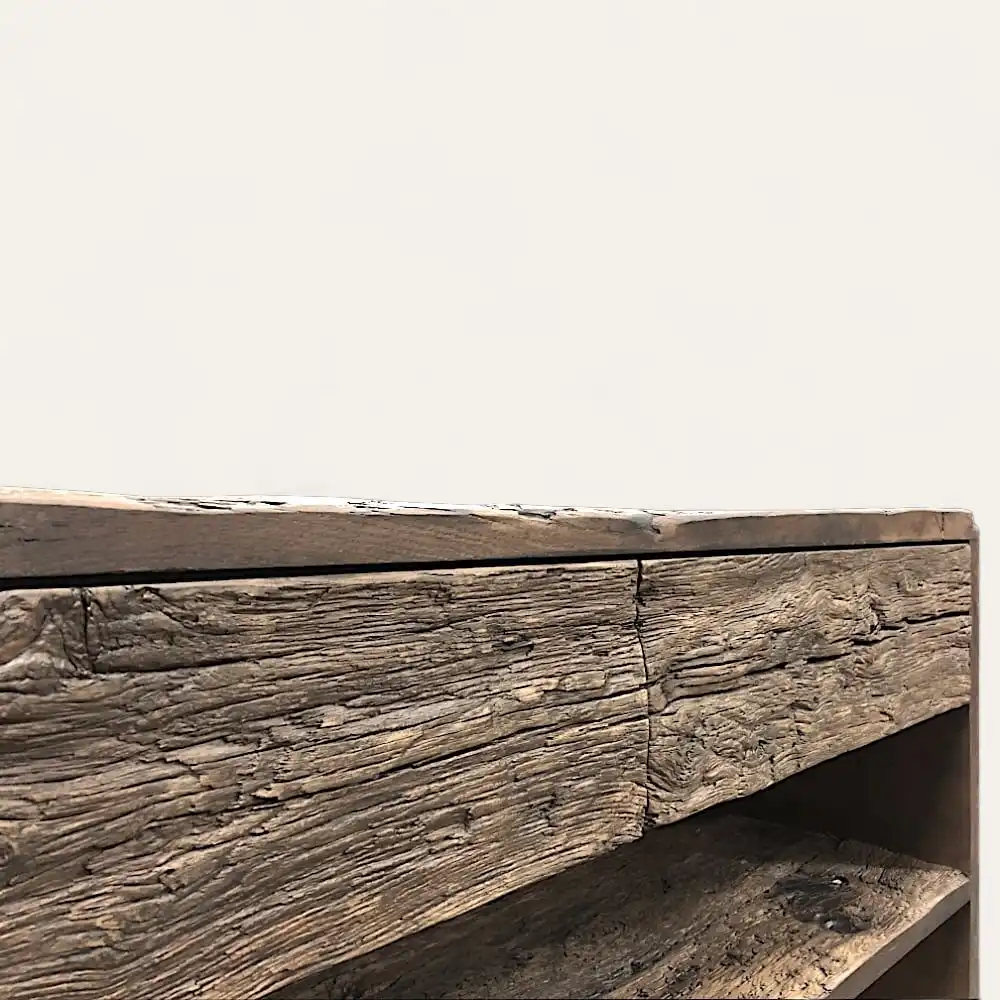  Vue rapprochée d'un meuble rustique avec une finition rustique, montrant un grain de bois texturé et patiné. La composition met en valeur les imperfections naturelles et les détails du bois. 