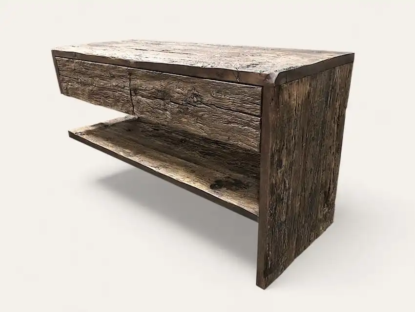 Une console rustique en bois avec un plateau rectangulaire, un seul tiroir et une étagère inférieure ouverte, en bois vieilli et patiné, idéale comme meuble de salle de bain en bois ancien.