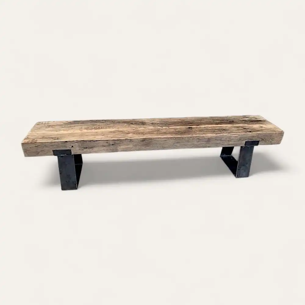  Un banc rustique en bois, ou banc rustique, avec un siège en planches épaisses et de solides pieds en métal noir se dresse fièrement sur un fond clair. 