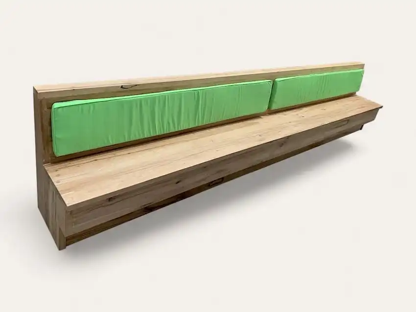 Un long banc en bois ancien avec des coussins verts est représenté sur un fond blanc uni.