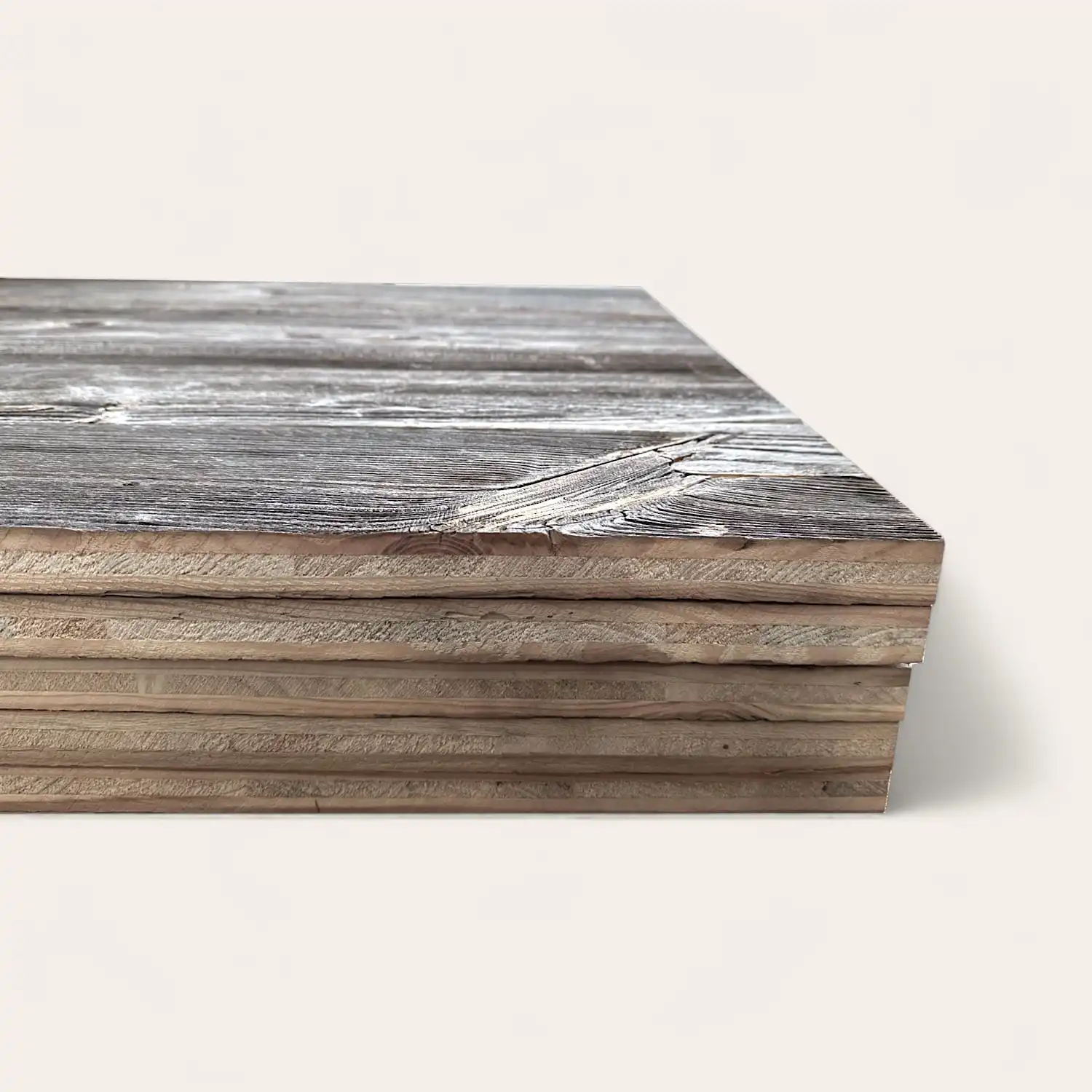  Empilement de planches de bois lamellé avec une surface grise texturée, affichée sur un fond clair uni, ressemblant à un panneau 3 plis vieux bois. 
