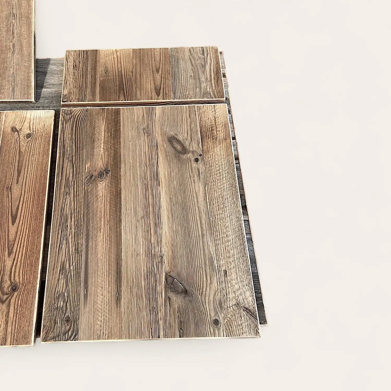  Des planches de bois au grain riche et sombre sont disposées pour montrer diverses orientations, sur un fond clair, créant une esthétique similaire à 3 plis vieux bois. 