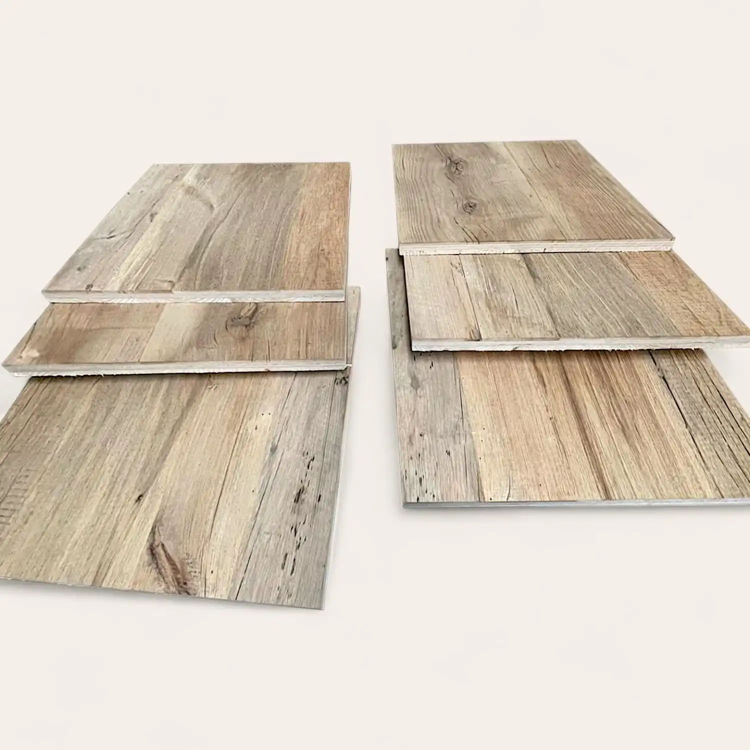  Trois échantillons de parquet vieux bois disposés sur une surface blanche, présentant différents motifs et couleurs de grain de bois. 
