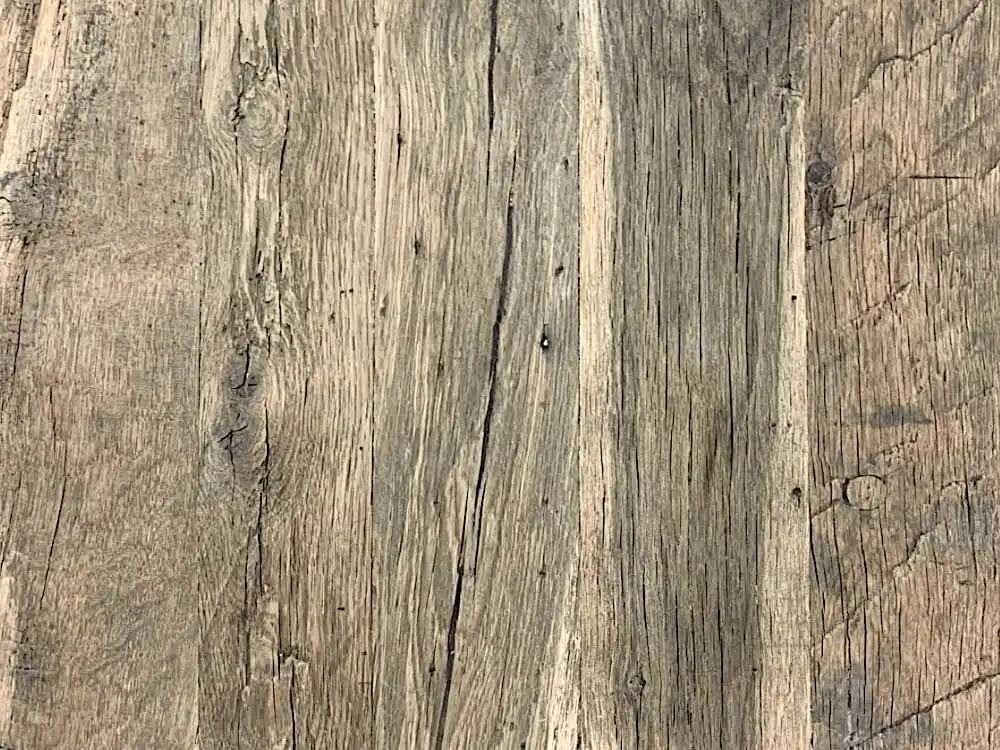 Gros plan d'une surface en bois vieilli avec des motifs de grain proéminents et des textures patinées, ressemblant à un panneau 3 plis vieux bois.