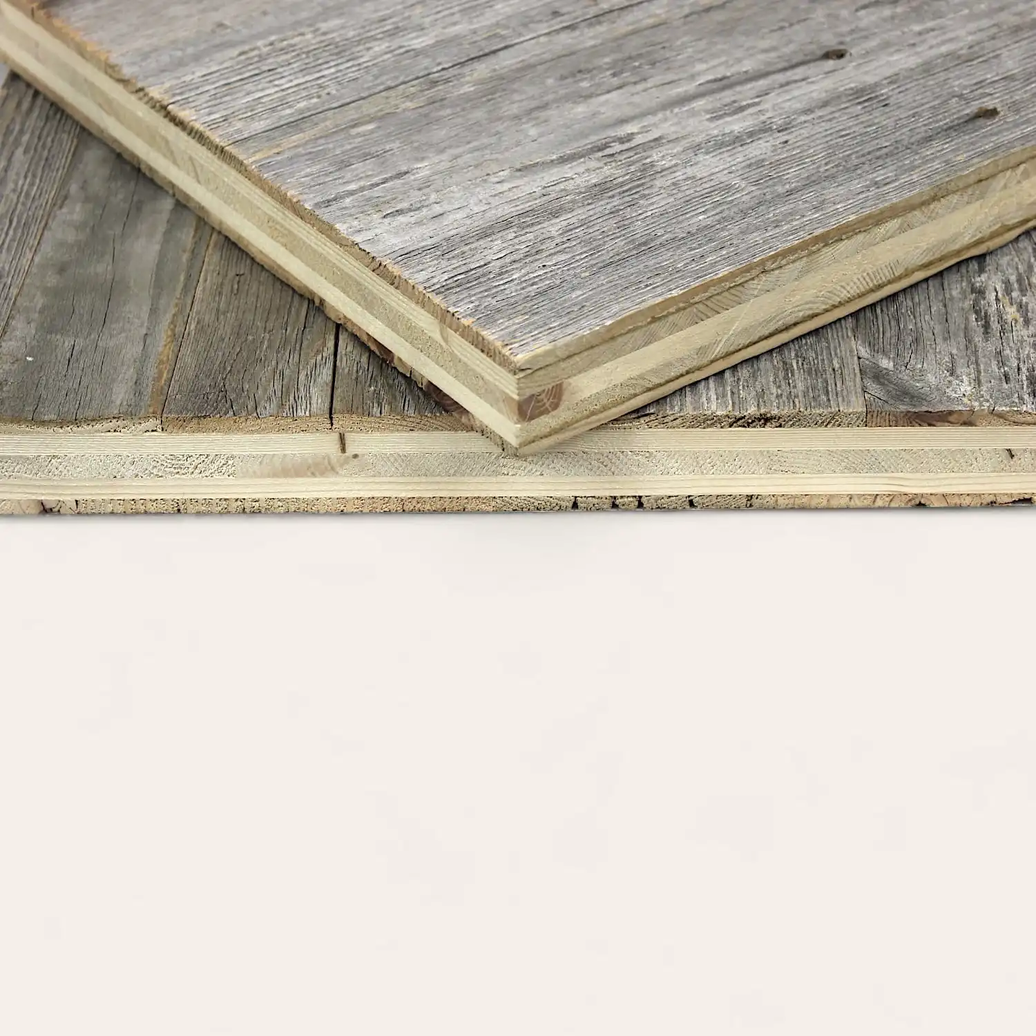  Vue rapprochée d'un échantillon de sol stratifié en bois appuyé contre un autre sur une surface en bois de panneau 5 plis. 