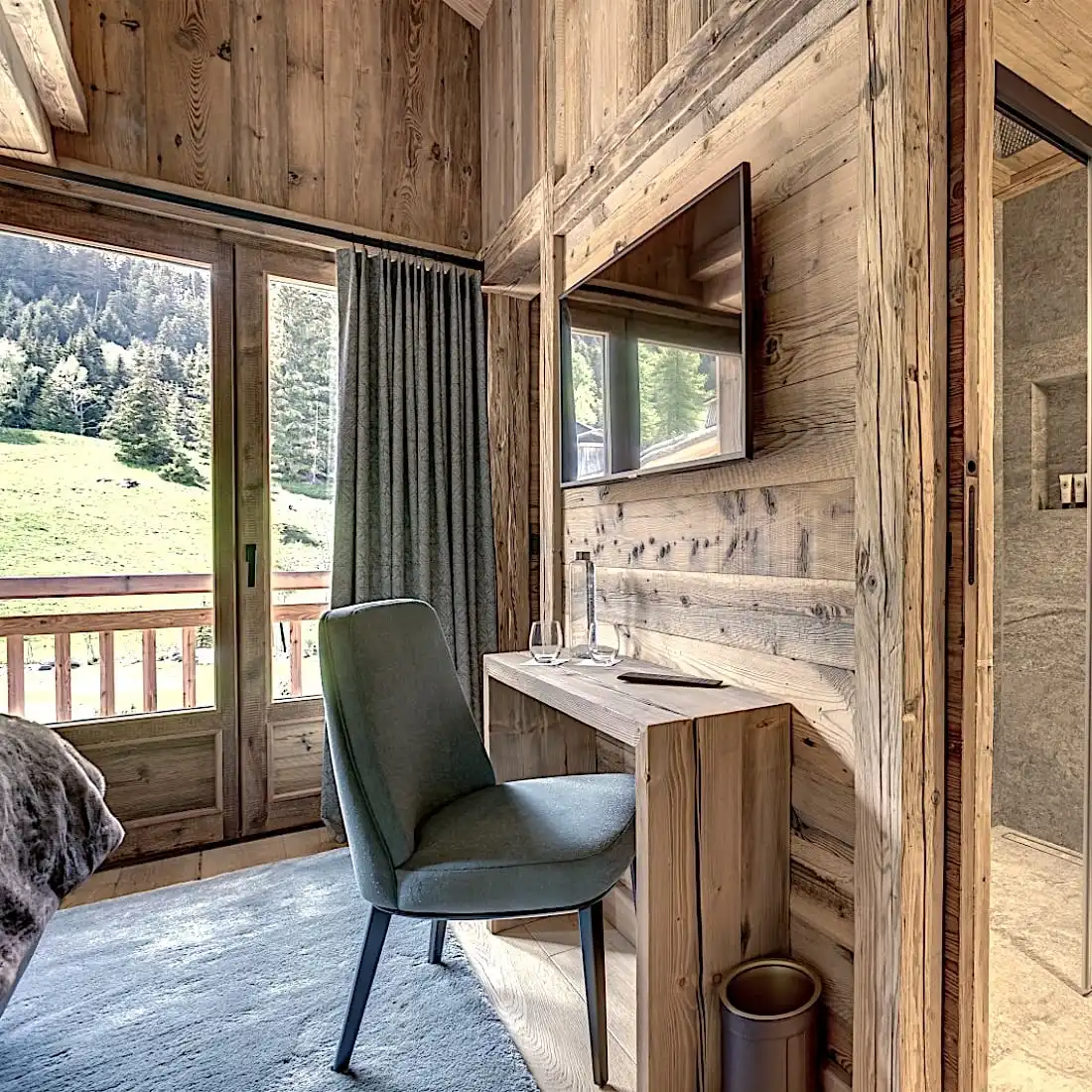  Un intérieur de cabane en bois confortable comprenant une chaise verte devant un bureau et de grandes fenêtres donnant sur un paysage de montagne boisé pittoresque. La cabane est agrémentée de panneaux vieux bois pour un aspect rustique authentique 
