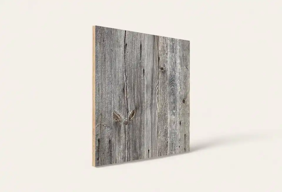 Une impression sur toile avec une texture de planche de bois patinée appuyée contre un mur uni.