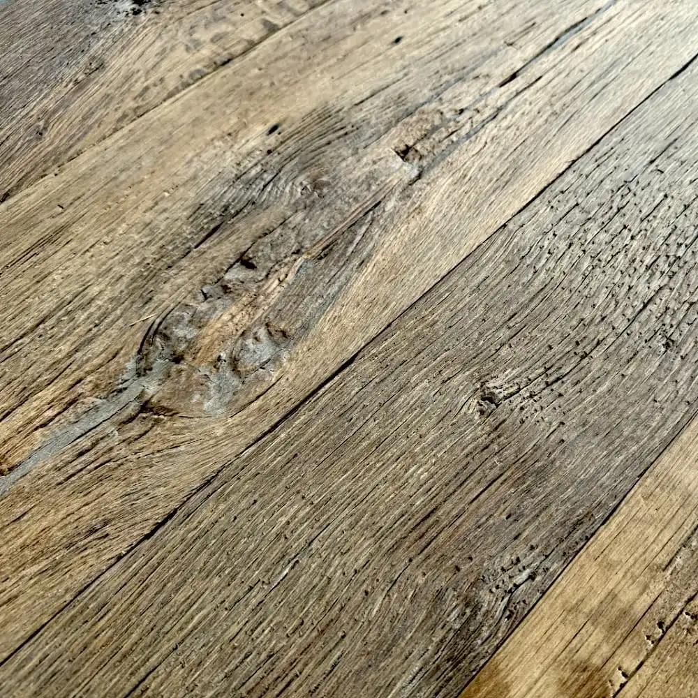 Gros plan d'une surface en bois patinée mettant en valeur ses motifs et textures de grain naturel, rappelant un ancien parquet en chêne (plancher ancien chêne). 