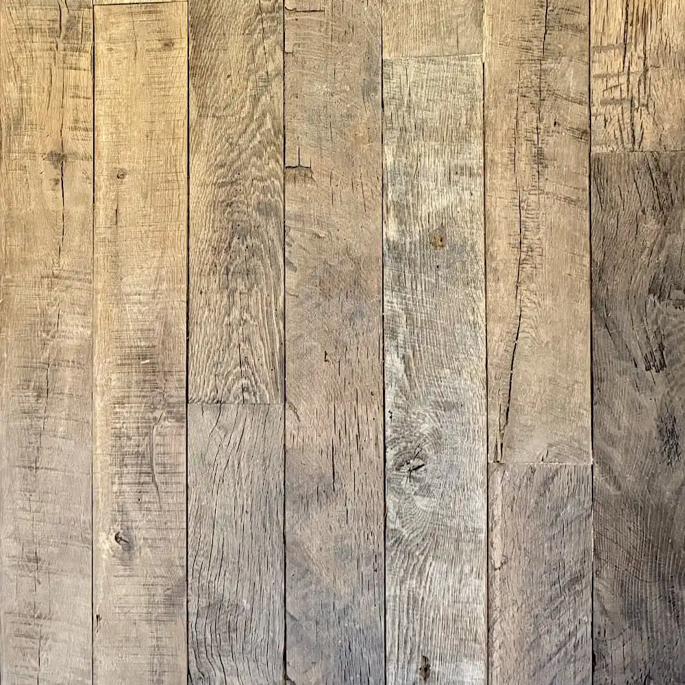  Gros plan d'un agencement vertical de planches de bois patinées dans différentes nuances de gris et de marron. Le plancher ancien bois présente des motifs de grains visibles et un aspect rustique. 