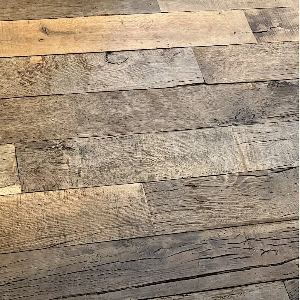  Une vue rapprochée du plancher ancien, mettant en valeur des planches de bois patinées avec diverses nuances et textures disposées horizontalement. 