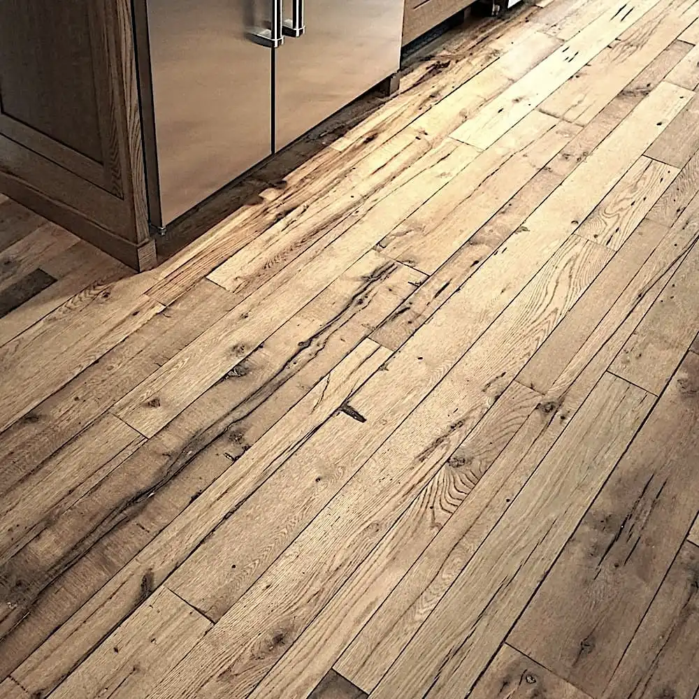  Un parquet en bois au fini naturel, rappelant le plancher ancien, est visible dans un coin cuisine à côté d'appareils électroménagers en acier inoxydable. 