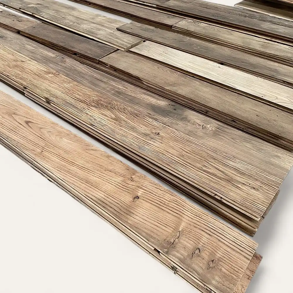  Plusieurs planches de bois de teintes variées, ressemblant à un parquet châtaignier rustique, disposées à plat sur une surface. 