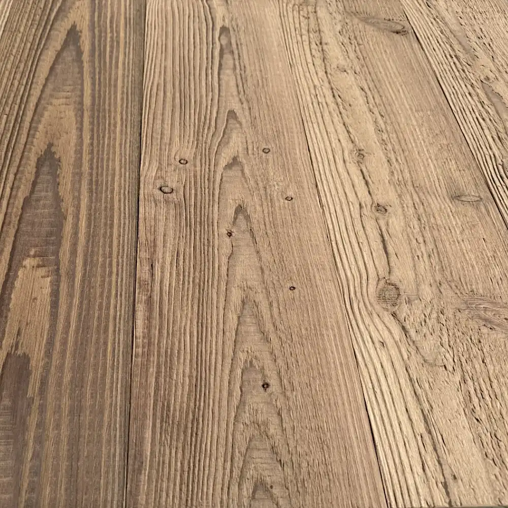  Gros plan d'une surface en bois avec des motifs de grain visibles et des nœuds naturels. Les planches du parquet ancien sapin varient en couleur du brun clair au brun foncé, mettant en valeur la texture et les imperfections naturelles du bois. 