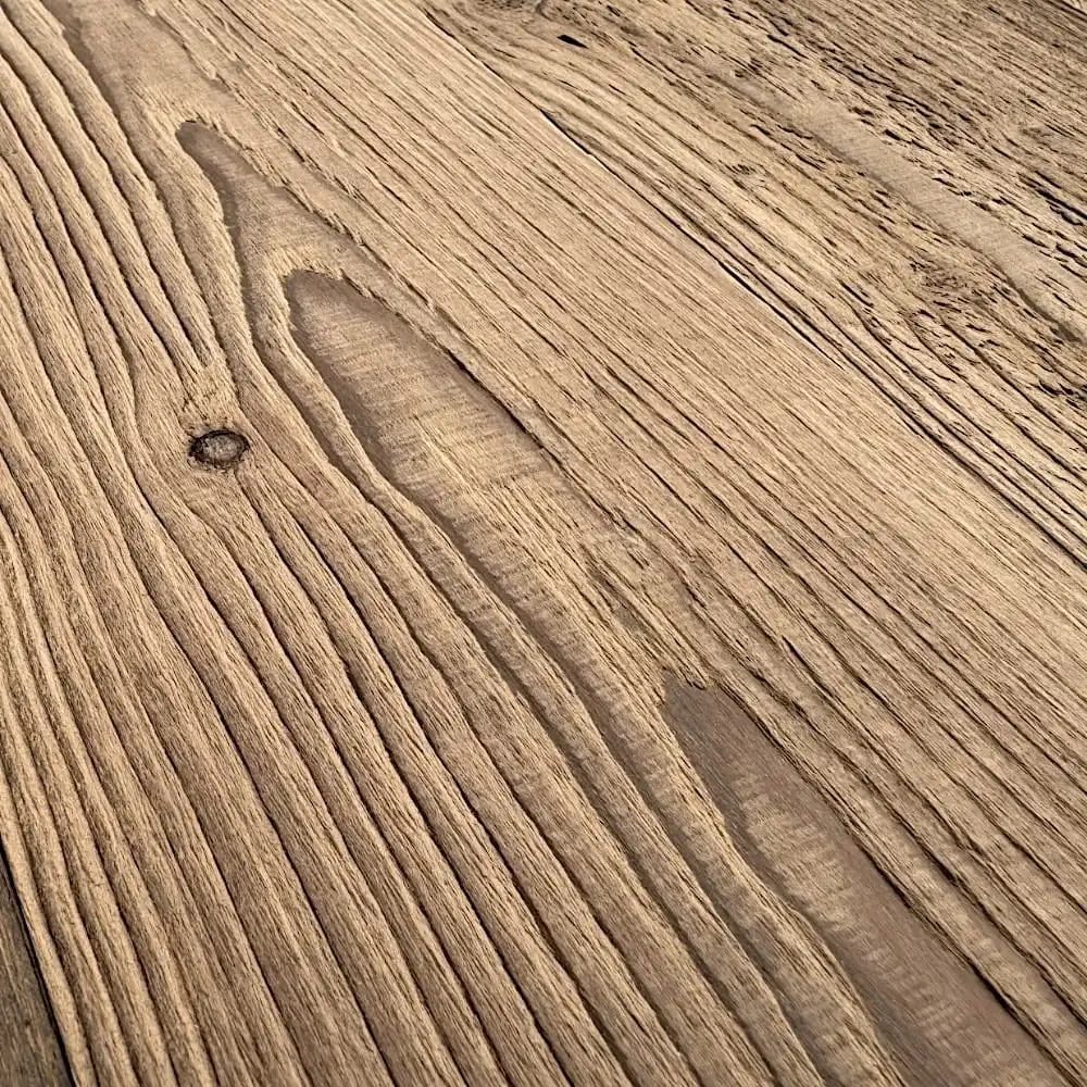  Gros plan d'une surface en bois texturée avec des motifs de grain et des nœuds distincts, rappelant un parquet antique ou du sapin. Le bois semble naturel et non poli. 