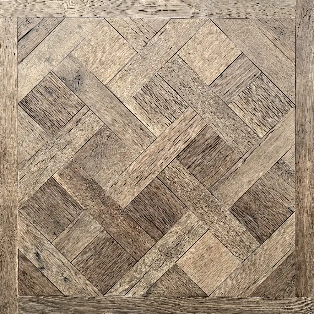  Une section carrée de parquet avec un motif géométrique complexe et imbriqué composé de planches de bois de différentes nuances de brun, rappelant le style classique du Parquet de Versailles ancien. 