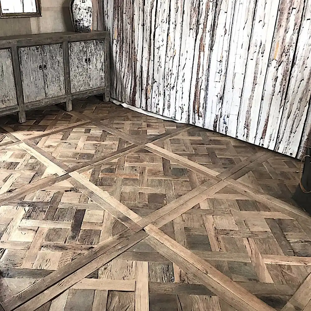  Une pièce avec du parquet versailles vieilli, un meuble vieilli et un mur en bois rustique. 