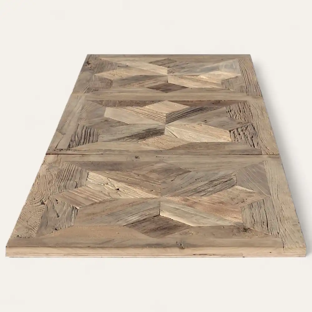  Une grande table en bois avec un motif géométrique sur sa surface, présentant différentes nuances de bois naturel, rappelant un parquet ancien motif étoile. 