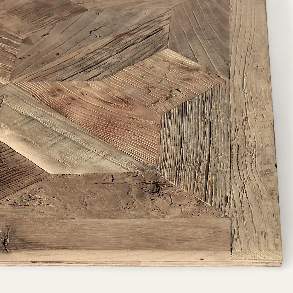  Gros plan d'un plateau en bois avec un motif géométrique composé de différentes nuances de planches de bois ressemblant à une étoile. La surface du parquet ancien présente un aspect rustique et patiné, ajoutant un charme intemporel. 
