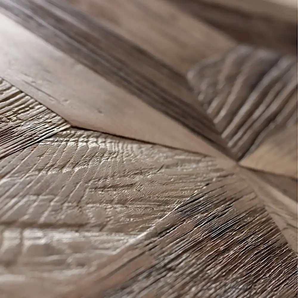  Gros plan d'une surface en bois présentant des motifs de grain et des textures complexes dans différentes nuances de brun, rappelant les motifs de parquet en étoile que l'on trouve dans les anciens domaines français. 