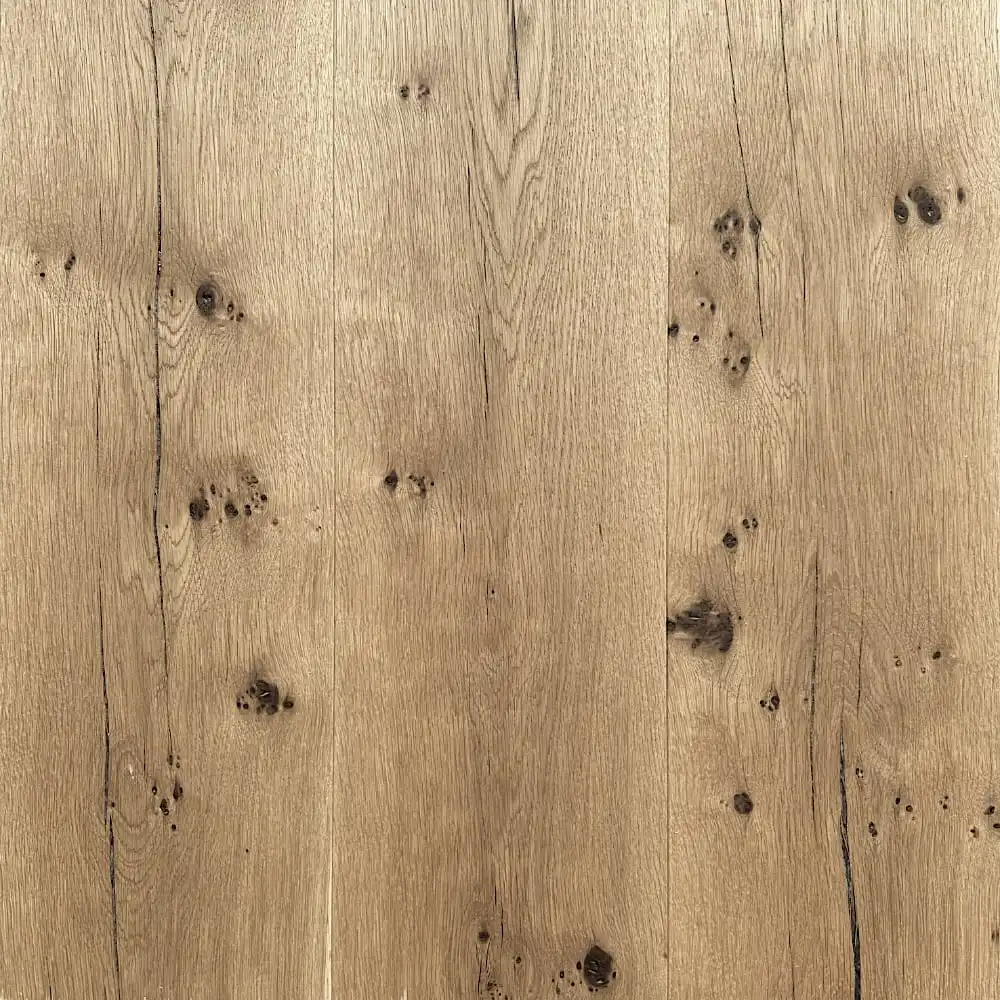  Gros plan d'une surface en bois avec un motif de grain naturel et des nœuds sombres épars, rappelant le parquet vieilli en chêne ancien. Le bois a une couleur marron clair et un aspect légèrement texturé. 