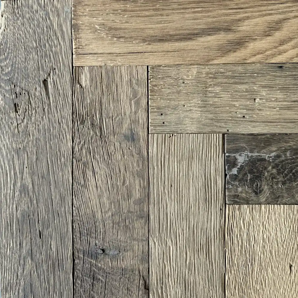  Gros plan de planches de bois disposées selon un élégant motif de parquet ancien, mettant en valeur différentes nuances de brun et des textures de grain de bois visibles. 