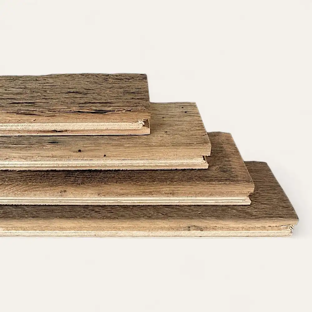  Quatre planches de bois empilées, rappelant un parquet ancien, présentant des épaisseurs variables et une finition marron clair. 