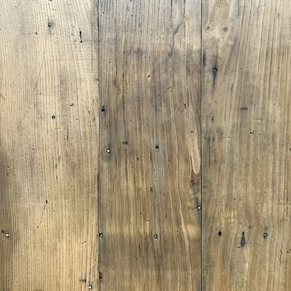  Trois planches verticales du plancher châtaignier présentent des motifs de grain visibles et quelques nœuds. Le bois semble patiné, dégageant un aspect naturel et rustique. 