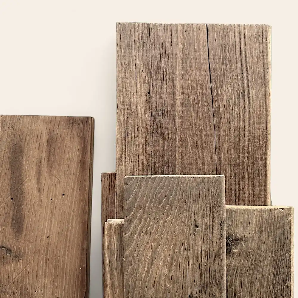  Plusieurs morceaux de planches de bois texturées de différentes tailles, rappelant le plancher ancien châtaignier, sont disposées verticalement sur un fond uni. 