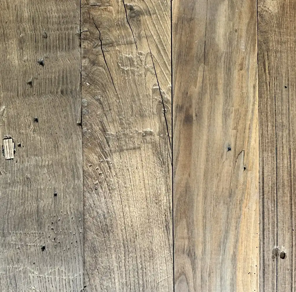  Gros plan d'une surface de planche de bois avec des grains, des nœuds et des textures visibles dans diverses nuances de brun, rappelant un plancher ancien. 