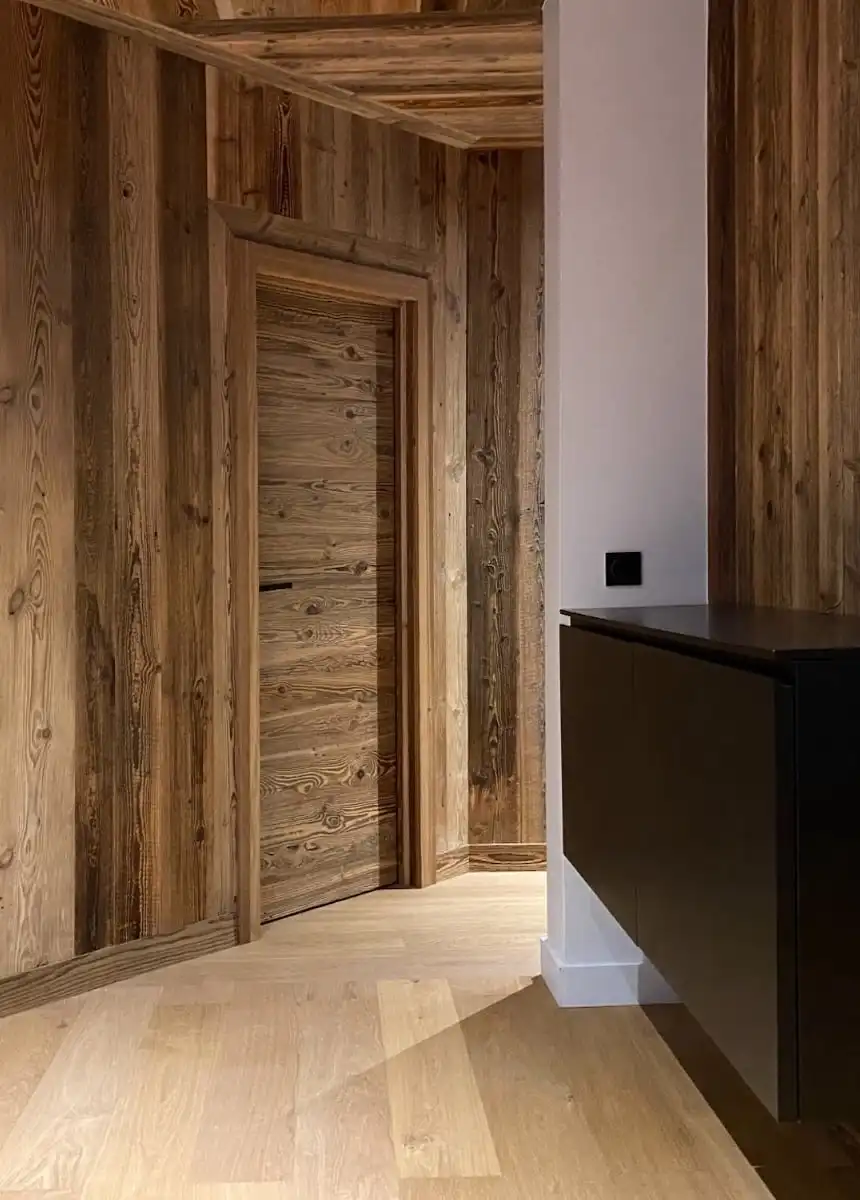 Une pièce avec des murs en bois vieilli et une porte de grange en bois.