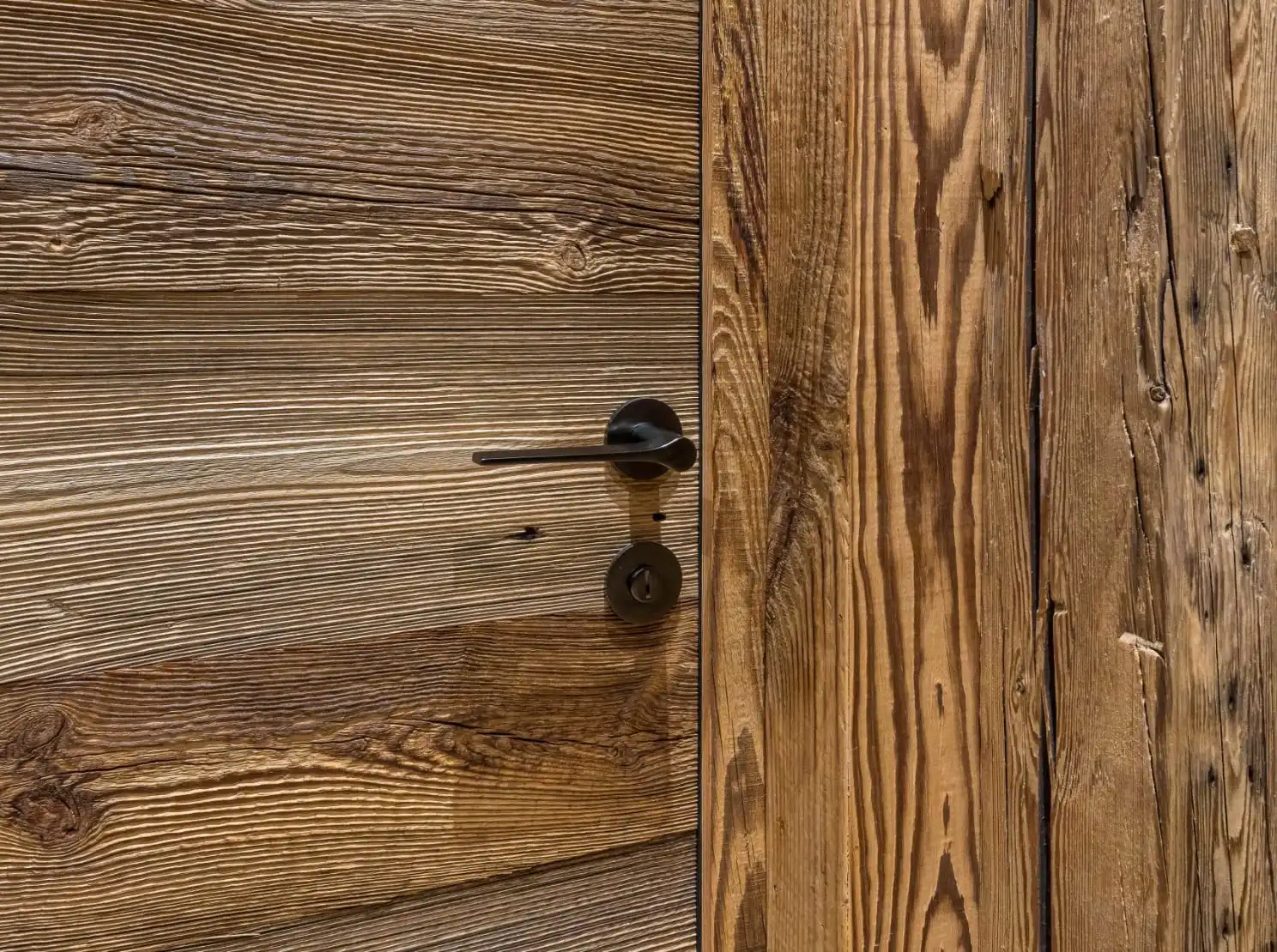 Une porte en bois de grange avec une poignée noire.