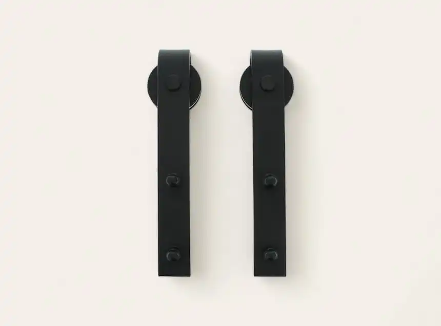 Deux roulettes de porte coulissante noires montées sur une surface blanche.